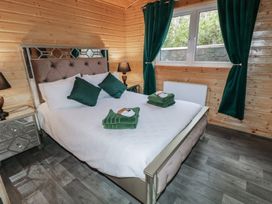 A bedroom with a bed with white bedding green pillows and towels wooden walls and floor at Railway Lodge in Dungiven Londonderry
