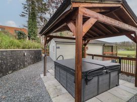 An outdoor hot tub with a wooden roof structure and gravel path next to a small building at Railway Lodge in Dungiven Londonderry