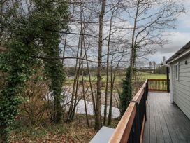 A balcony with wooden railing overlooking trees and a river at Railway Lodge in Dungiven Londonderry