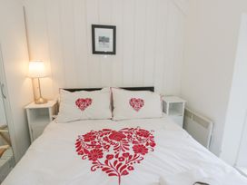 A bedroom featuring a bed with decorative pillows and a lamp at Brynmorfa in Llandysul