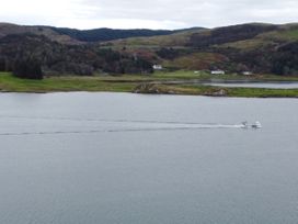 A boat on water with hills and houses in the background at Scarba in Balvicar, Isle Of Seil