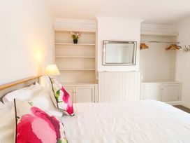 A bedroom with a bed and shelves at Highland House Sheringham
