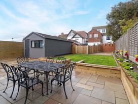 A garden with a dining table and chairs in front of a shed at Highland House in Sheringham