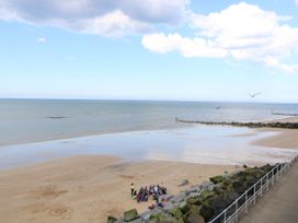 A beach scene with people gathered on the sand at Highland House in Sheringham