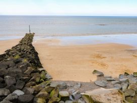 A beach with a rock pier and ocean at Highland House Sheringham