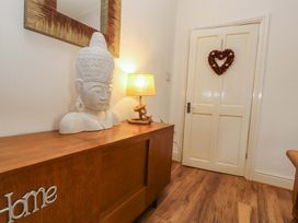 An entryway with a wooden cabinet, bust sculpture, lamp, and door at 2 The Crescent