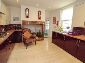 A kitchen with a stove, sink, and chair at 2 The Crescent
