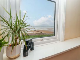 A window with a view of the sea and binoculars on the ledge at 2 The Crescent