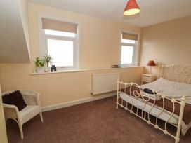 A bedroom with a bed, armchair and windows at 2 The Crescent