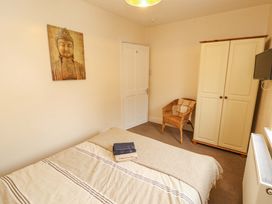 A bedroom with a bed, wardrobe, chair, and wall art at 2 The Crescent