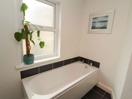 A bathroom with a bathtub and a plant on the windowsill at 2 The Crescent