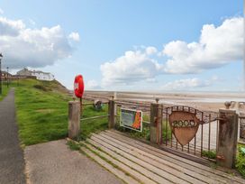 A view of a pathway leading to a beach with a life buoy at 2 The Crescent