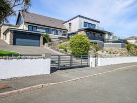 A modern multi level house with a driveway garage and garden behind a metal gate at Seaddler in Trearddur Bay