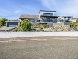 A modern house with a garage stone walls and stairs in front at Seaddler Trearddur Bay