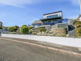 A modern house with glass balconies and stone retaining walls on a sloped lot at Seaddler in Trearddur Bay