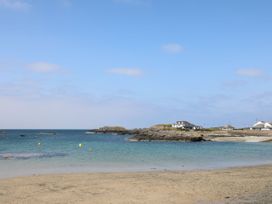 A sandy beach with rocks and houses near the coastline at Seaddler in Trearddur Bay