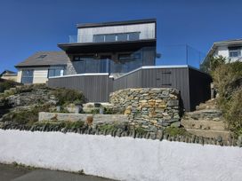 An outdoor view of a house with a glass railing and stone walls at Seaddler Trearddur Bay