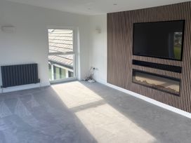 A living room with a window, radiator, television, and fireplace at Seaddler in Trearddur Bay