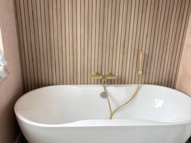 A bathtub with a gold tap and hose at Seaddler Trearddur Bay