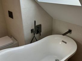 A bathroom with a bathtub and toilet at Seaddler, Trearddur Bay