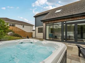 An outdoor area with a hot tub and stone patio at Seaddler in Trearddur Bay