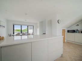 A kitchen with a dining table and chairs at Seaddler in Trearddur Bay