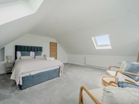 A bedroom with a bed and armchair at Seaddler in Trearddur Bay