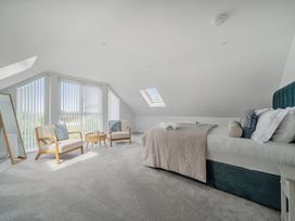 A bedroom with a bed and chairs at Seaddler in Trearddur Bay