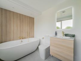 A bathroom featuring a bathtub, toilet, sink, and mirror at Seaddler in Trearddur Bay