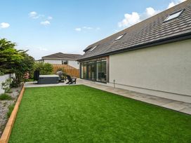 A garden with grass and a hot tub at Seaddler in Trearddur Bay