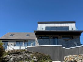 A house with a balcony and stone wall at Seaddler in Trearddur Bay