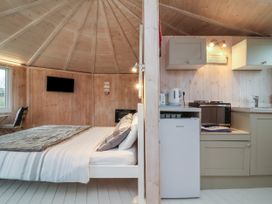 A bedroom with a bed and a wall-mounted TV next to a kitchen area with cabinets a microwave and a mini fridge at Hartland Quay near Hartland