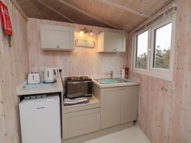 A small kitchen with a fridge, toaster, kettle, oven, stove, sink, cabinets, and a window at Hartland Quay near Hartland
