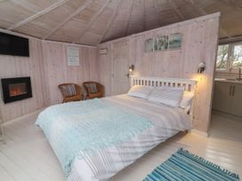 A bedroom with a double bed two chairs a wall mounted TV and fireplace at Shipload Bay near Hartland