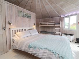 A bedroom with a double bed and bunk beds in a wooden cabin at Shipload Bay near Hartland