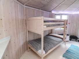 A room with wooden bunk beds and a blue striped rug at Shipload Bay near Hartland