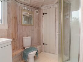 A bathroom with a toilet with a towel on the seat wood paneled walls a shower enclosure a mirror and a cabinet at Shipload Bay near Hartland