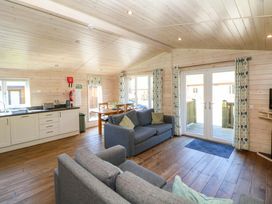A living room with a sofa and kitchen area at Dovestone Luxury Lodges (sleeps 4)- pet free Greenfield