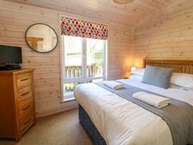 A bedroom with a bed, dresser, and window at Dovestone Luxury Lodges (sleeps 4)- pet free Greenfield