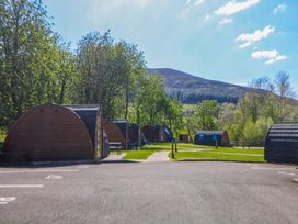 A view of wooden pods on green grass with trees and a mountain at Dovestone Luxury Lodges (sleeps 4)- pet free in Greenfield