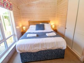 A bedroom with a bed and bedside table at Dovestone Luxury Lodges (sleeps 4) - pets welcome, Greenfield