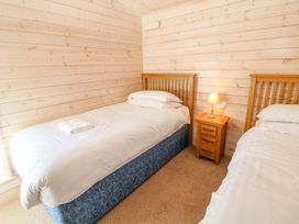 A bedroom with two beds and a nightstand with a lamp at Dovestone Luxury Lodges (sleeps 4) - pets welcome, Greenfield
