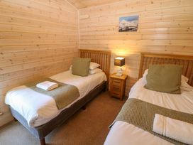 A bedroom with two single beds and a bedside table at Dovestone Luxury Lodges (sleeps 6) - pet free, Greenfield