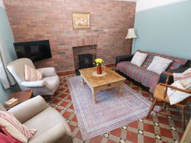 A living room with a brick fireplace wooden coffee table and patterned rug at Llanwern Farm in Fishguard