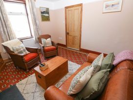 A sitting room with leather chairs wooden chest and paintings on the wall at Llanwern Farm in Fishguard