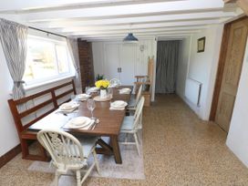 A dining room with a wooden table set with plates and glasses and chairs with cushions at Llanwern Farm in Fishguard