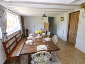 A dining room with a wooden table set for six people with dishes glasses and yellow flowers Llanwern Farm Fishguard