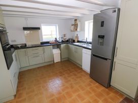 A kitchen with green cabinets a stainless steel refrigerator a double sink and a dishwasher at Llanwern Farm in Fishguard