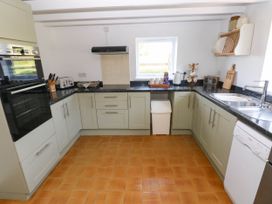 A kitchen with cabinets a window a sink a dishwasher and various kitchen appliances at Llanwern Farm Fishguard