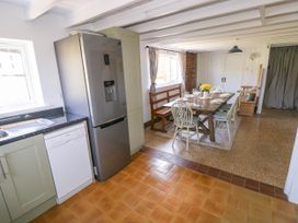A kitchen area with a refrigerator dishwasher and sink next to a dining table with chairs and a bench at Llanwern Farm in Fishguard